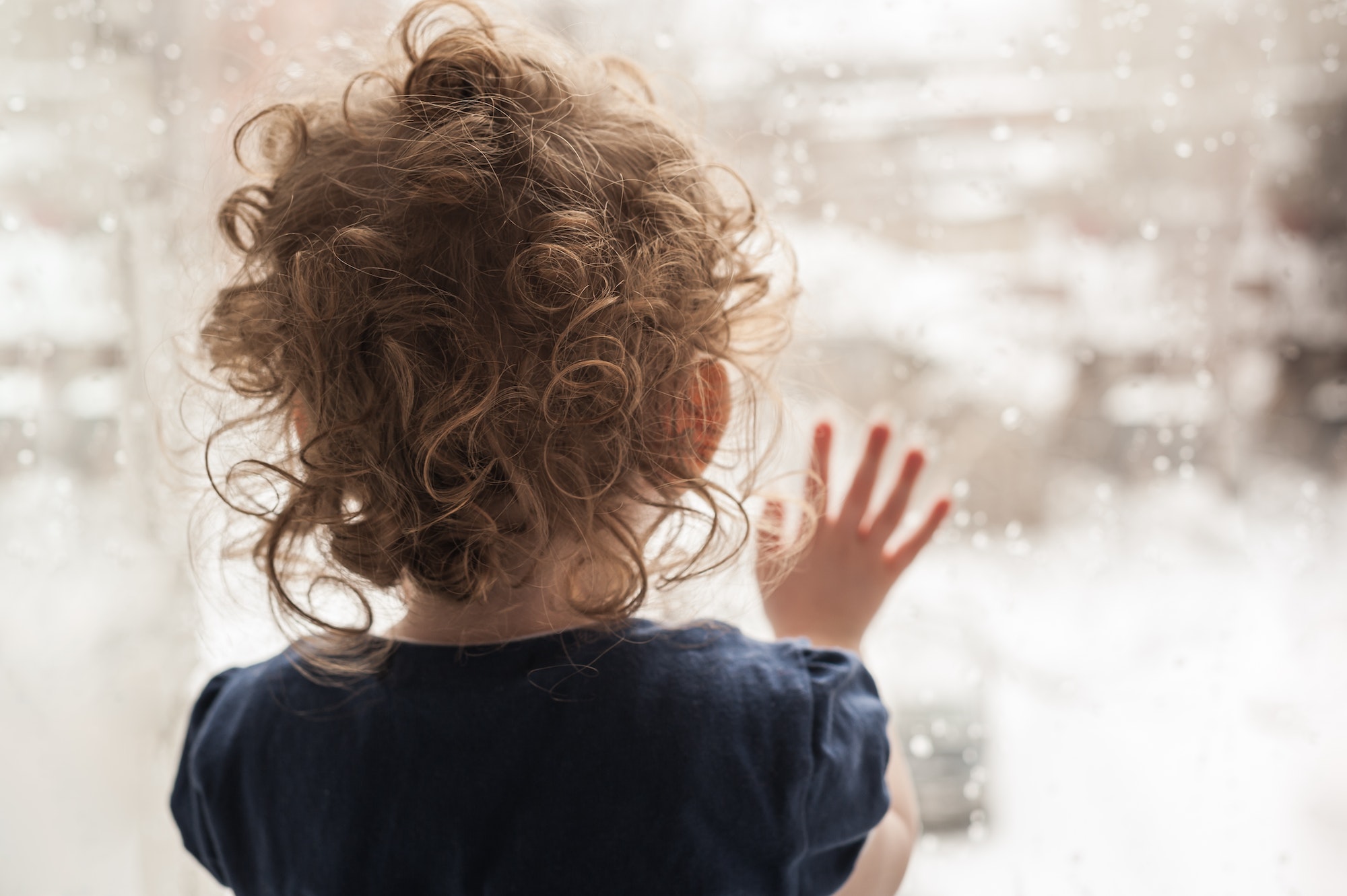 Sad child looking out the window.