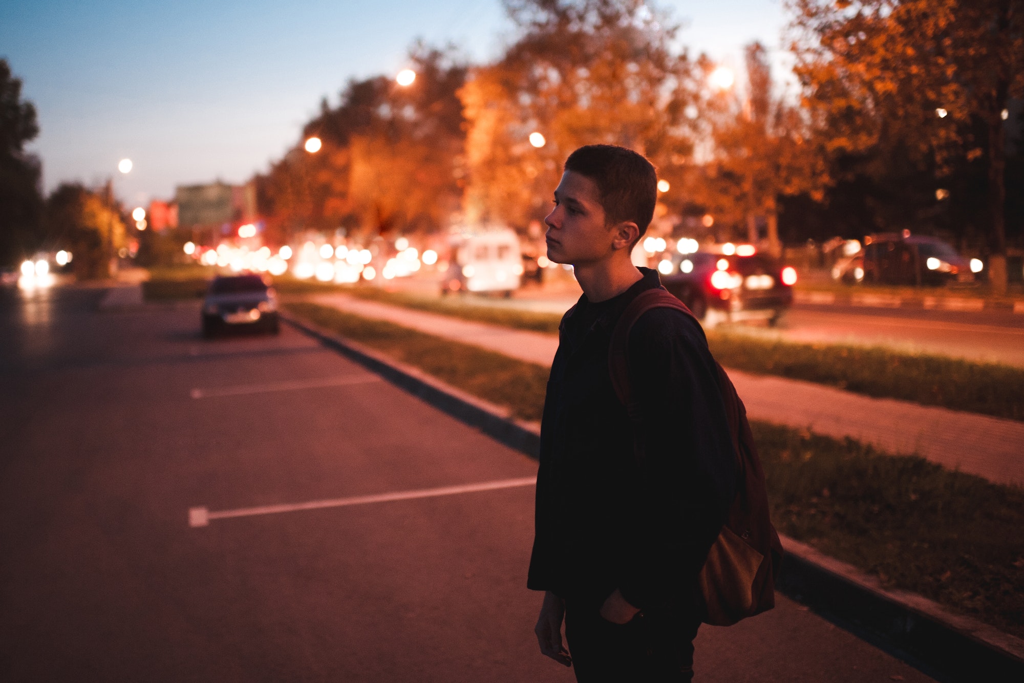 Teen boy standing at parking lot at night. Blurred focus.
