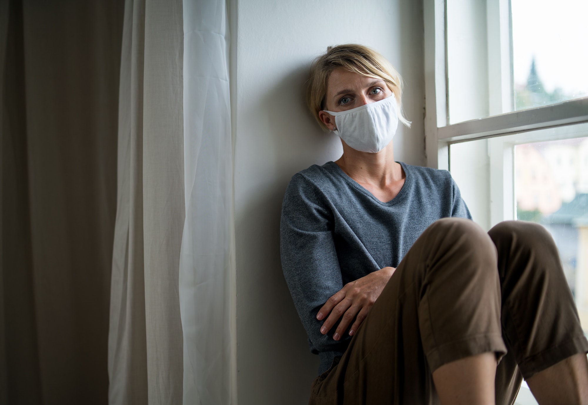 Woman indoors at home feeling stressed, mental health and coronavirus concept.