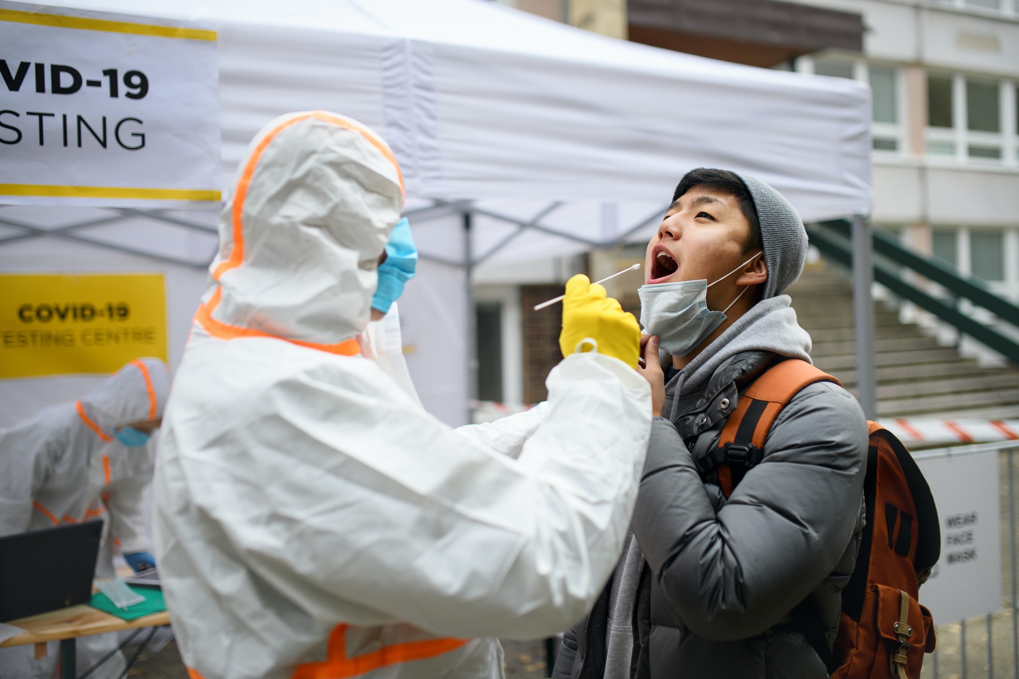 Young man in covid-19 testing center outdoors on street, coronavirus concept.