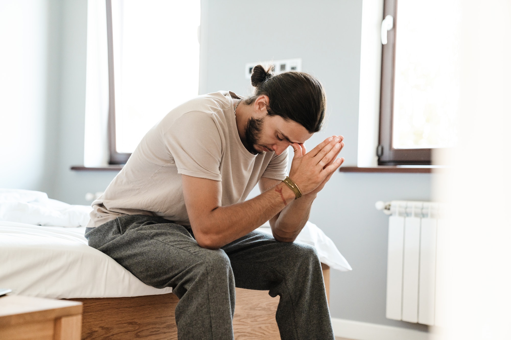 Young man in depression sitting on bed