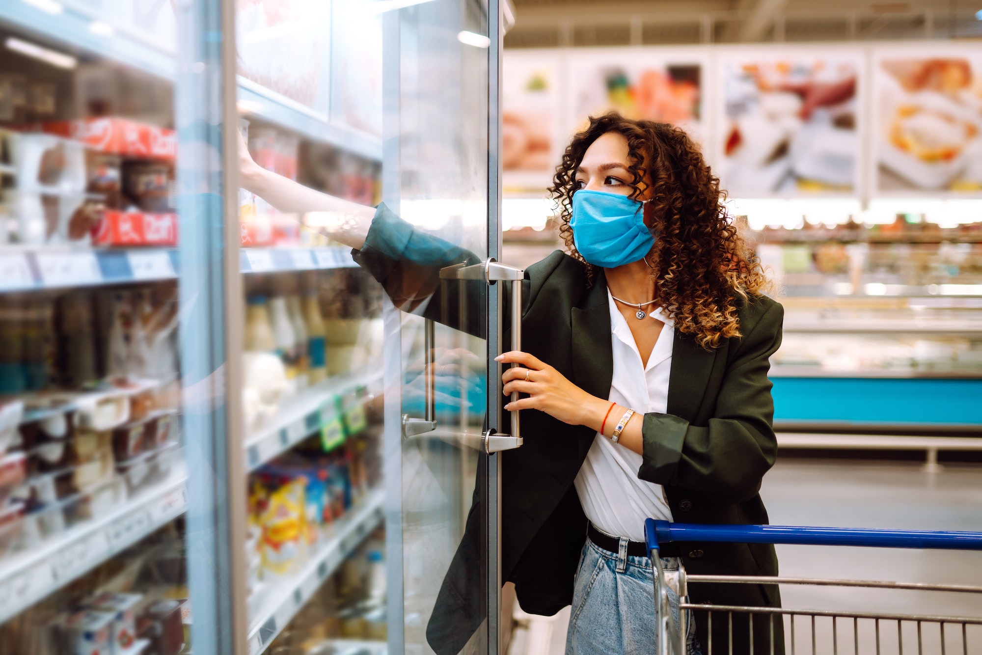 Young woman wearing face mask buying in supermarket. Shopping during the pandemic. Covid-2019.