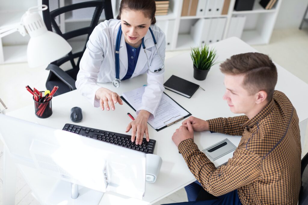 The doctor explains the problem to the patient on the computer.