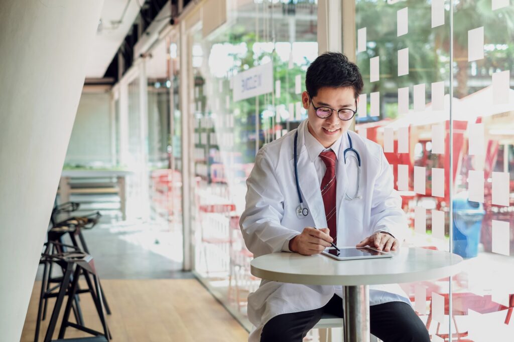 Doctor using his tablet in medical office, Checking data of patients with digital tablet.